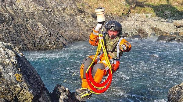 Coast guard being hoisted above water