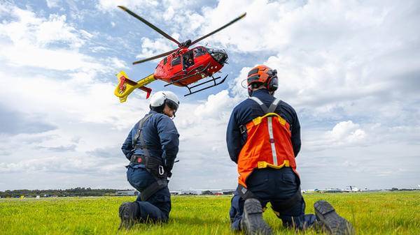 Two rescue workers watching helicopter land