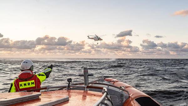 Coast guard pointing at helicopter flying over sea