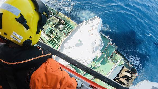 Helicopter paramedic looking out of helicopter onto boat