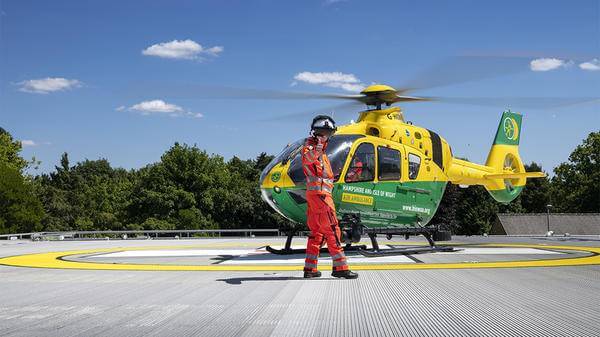 Helicopter pilot on landing deck doing thumbs up as helicopter is about to take off