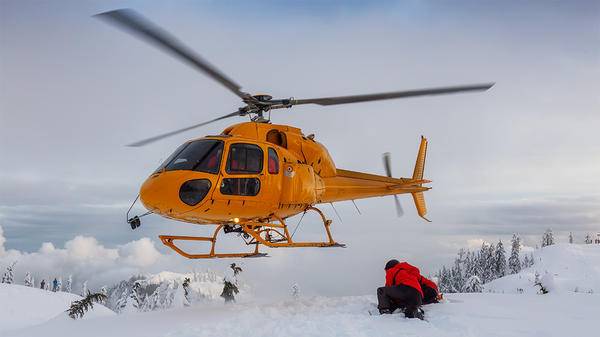 Orange helicopter flying over snow