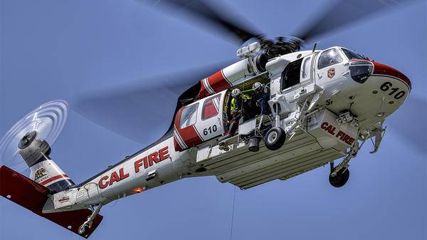 Helicopter in sky with fire brigade about to hoist out of it