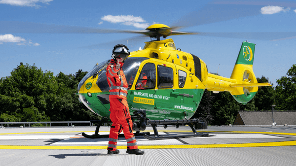 Crewmember does a thumbs-up in front of HIOWAA air ambulance helicopter