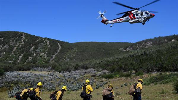 Helicopter flying above field with workers on