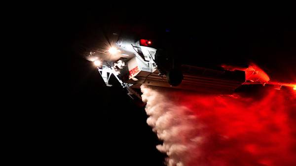 Helicopter dropping fire retardant at night
