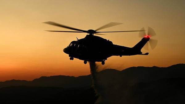 Helicopter dropping fire retardant at dusk