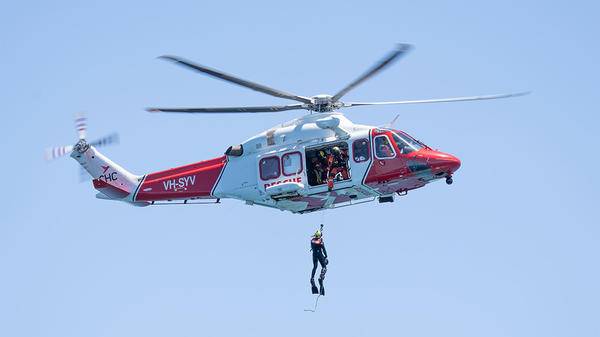 Helicopter flying with person hoisted out