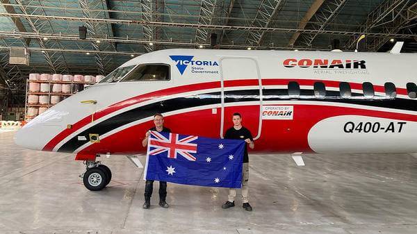 Pilots holding Australian flag next to plane