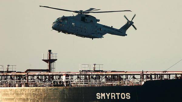 Military helicopter flying over sea next to ship