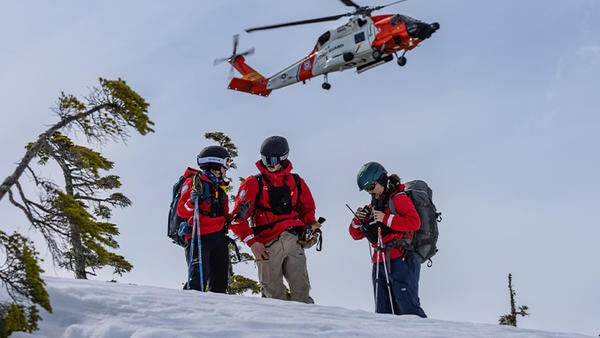 Search and rescue team in the snow with helicopter above