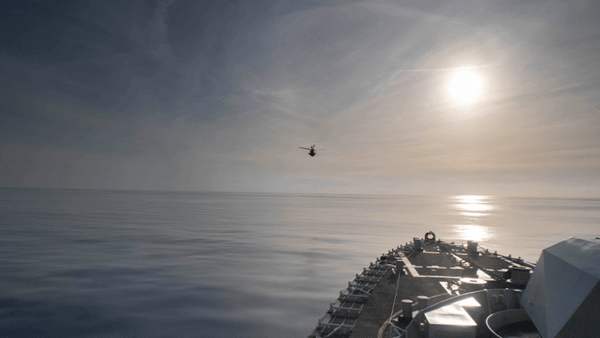 Ship in calm seas with helicopter flying in the distance