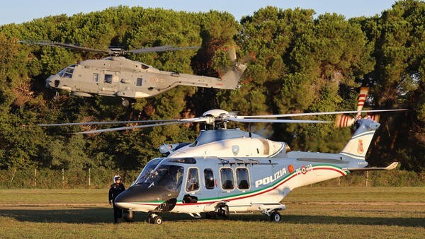Parked helicopter with helicopter taking off in background