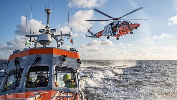 Helicopter flying above sea next to boat