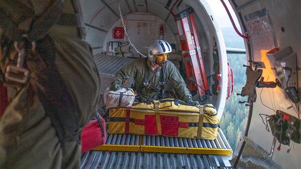 Helicopter paramedic pushing cargo out of helicopter