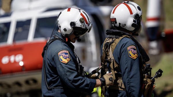 Firefighter sorting out other firefighters harness