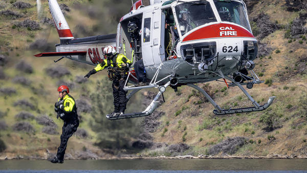 Cal fire fighter jumping into water from helicopter
