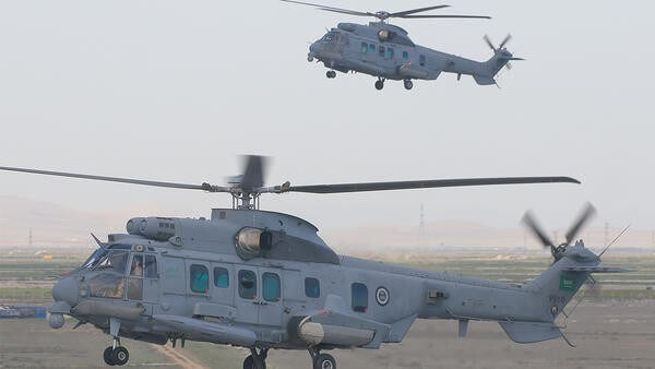 Two grey helicopters in flight