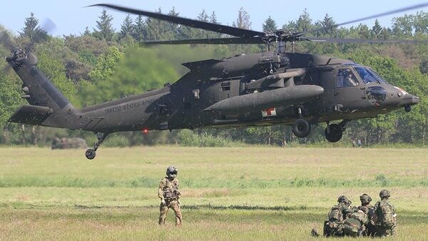 Military next to helicopter that is taking off