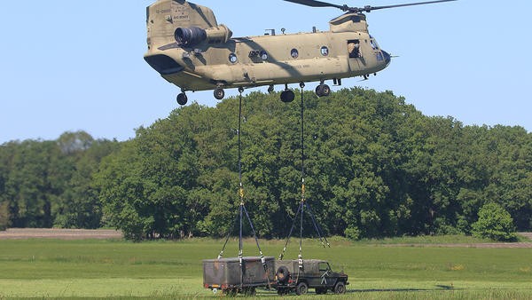 Helicopter preparing to lift up jeep and trailer