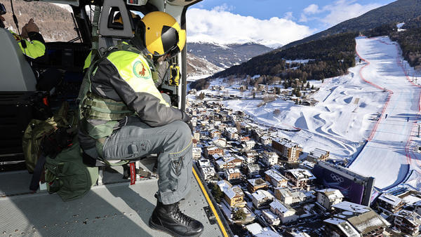 Man looking out of helicopter over snowy Italian town