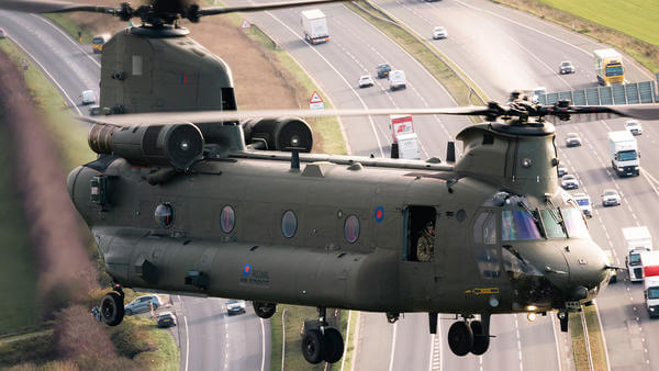 Military helicopter flying over motorway