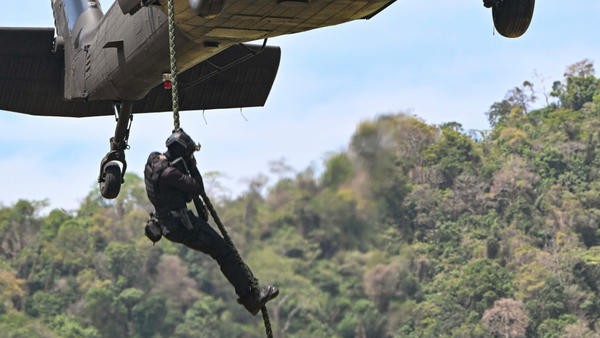 Military personnel hoisted from helicopter rope
