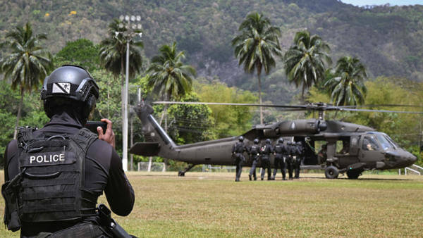 Police personnel taking photo of other police getting into helicopter