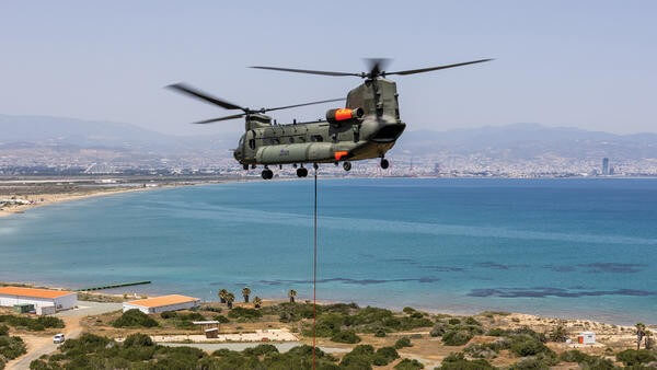 Helicopter carrying a firefighting bucket over the coastline