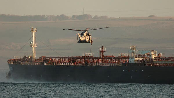 Helicopter flying above sea next to ship
